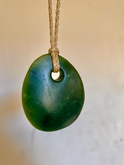 Green pounamu pendant on a braided cord